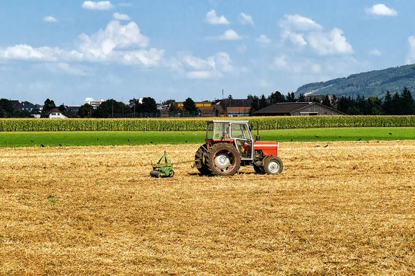 Tractor con arado haciendo algunos trabajos agrícolas de temporada en el campo — Foto de Stock