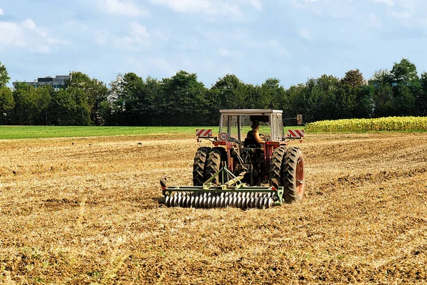 Traktor dengan bajak melakukan pekerjaan musiman pertanian di lapangan — Stok Foto