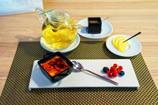 Десерт з кремової карамелі, що подається з ягодами та чайником — стокове фото
