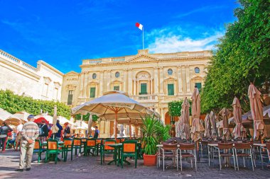 People resting at open air cafes of Republic Square Valletta clipart