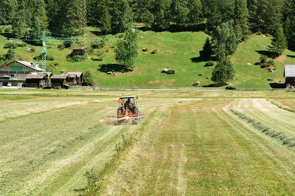 Traktor memotong jerami di padang rumput Swiss — Stok Foto