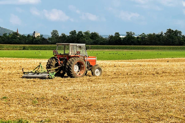 Trator com arado fazendo trabalho sazonal agrícola no campo — Fotografia de Stock