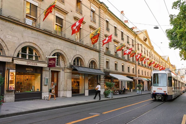 Tren y personas en Rue Corraterie Street Banderas de Suiza Ginebra — Foto de Stock