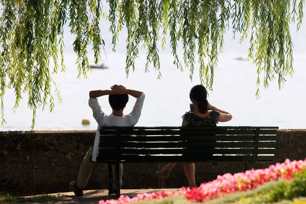 Mladý pár sedící na lavičce v Ouchy Lausanne — Stock fotografie