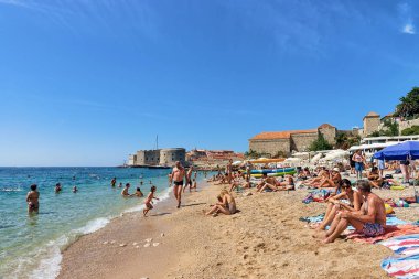 İnsanlar plajda Adriyatik Denizi ve Dubrovnik kale