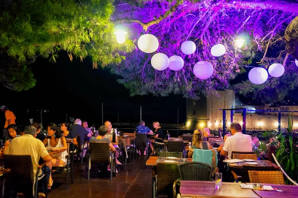 Люди на вулиці кафе з ліхтар висвітлюватися в ніч Dubrovnik — стокове фото
