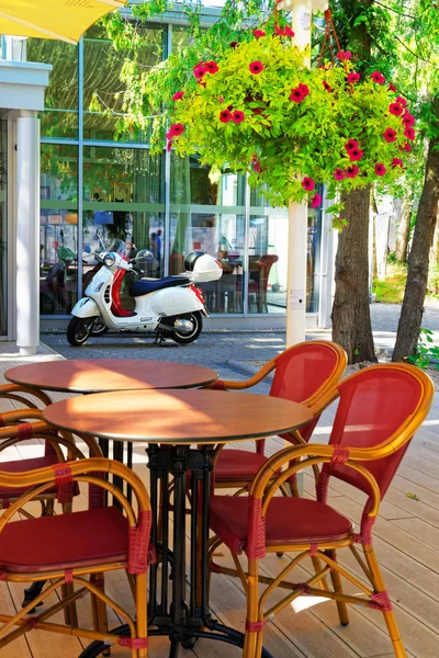 Pouliční kavárna se stoly a židlemi a skútr — Stock fotografie