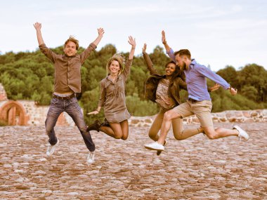 Grup gülümseyen genç çok ırklı arkadaşlar kadar atlamak için