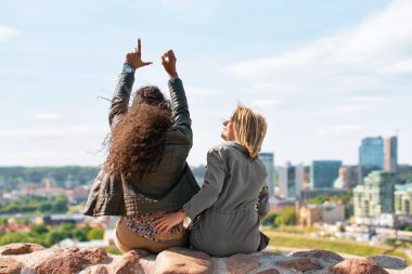 İki kız gösterilen işareti şehir panorama zevk parmakları ile seviyorum.