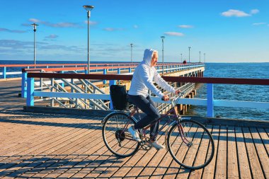 Kadın kıdemli binicilik bisiklet deniz Köprüsü'nde in Palanga