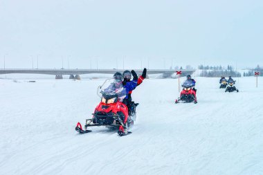İnsanların ellerini sallayarak ve snowmobile donmuş göl Rovaniemi içinde sürme