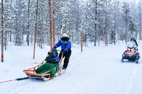Familjen ridning på husky hundar hundspann och snöskoter i Rovaniemi — Stockfoto