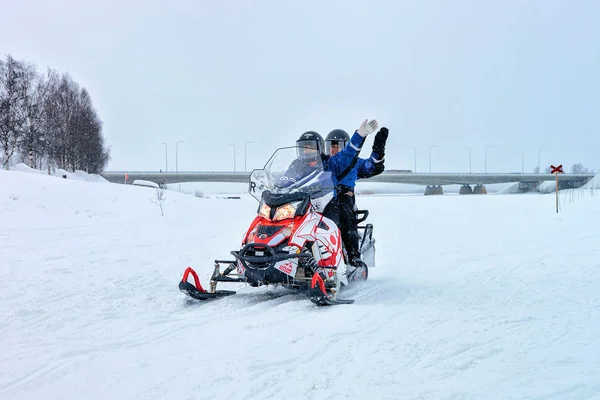 Personer viftande händer medan ridning snöskoter på frusna sjön Rovaniemi — Stockfoto