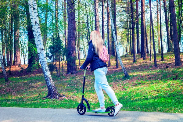 Young woman on push scooter in park Druskininkai