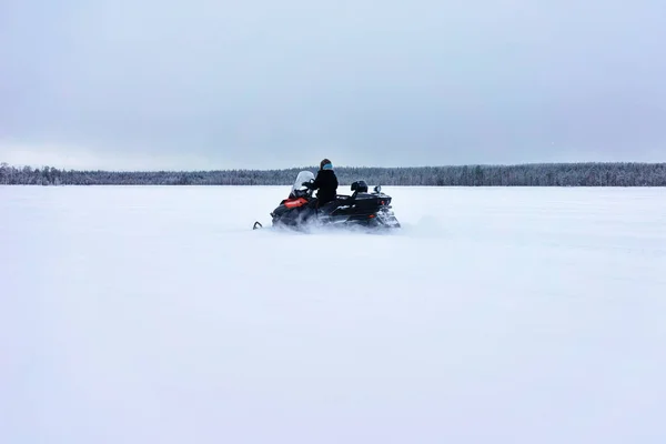 Mujer conduciendo moto de nieve en el lago congelado en invierno Rovaniemi Finlandia —  Fotos de Stock