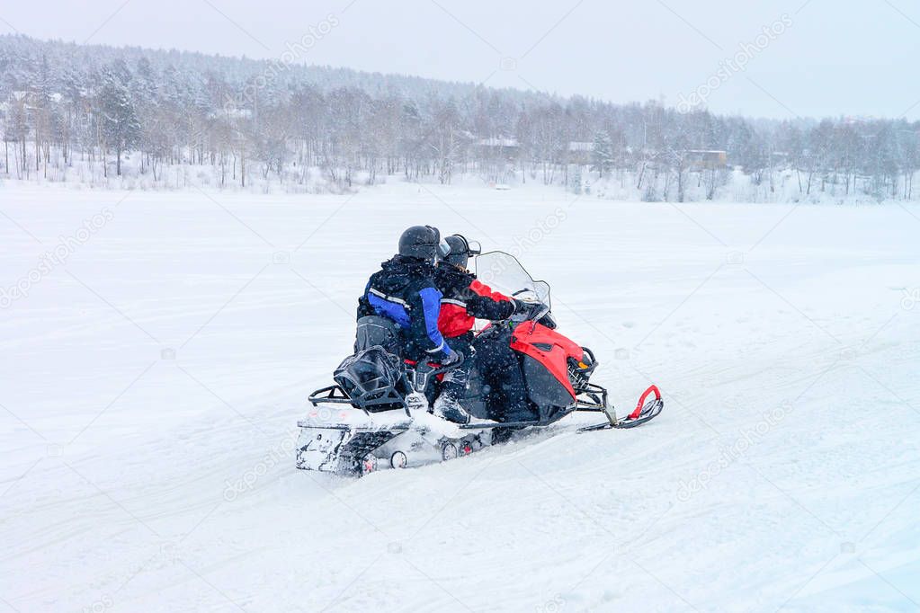 People ride snowmobiles in frozen snow lake at winter Rovaniemi