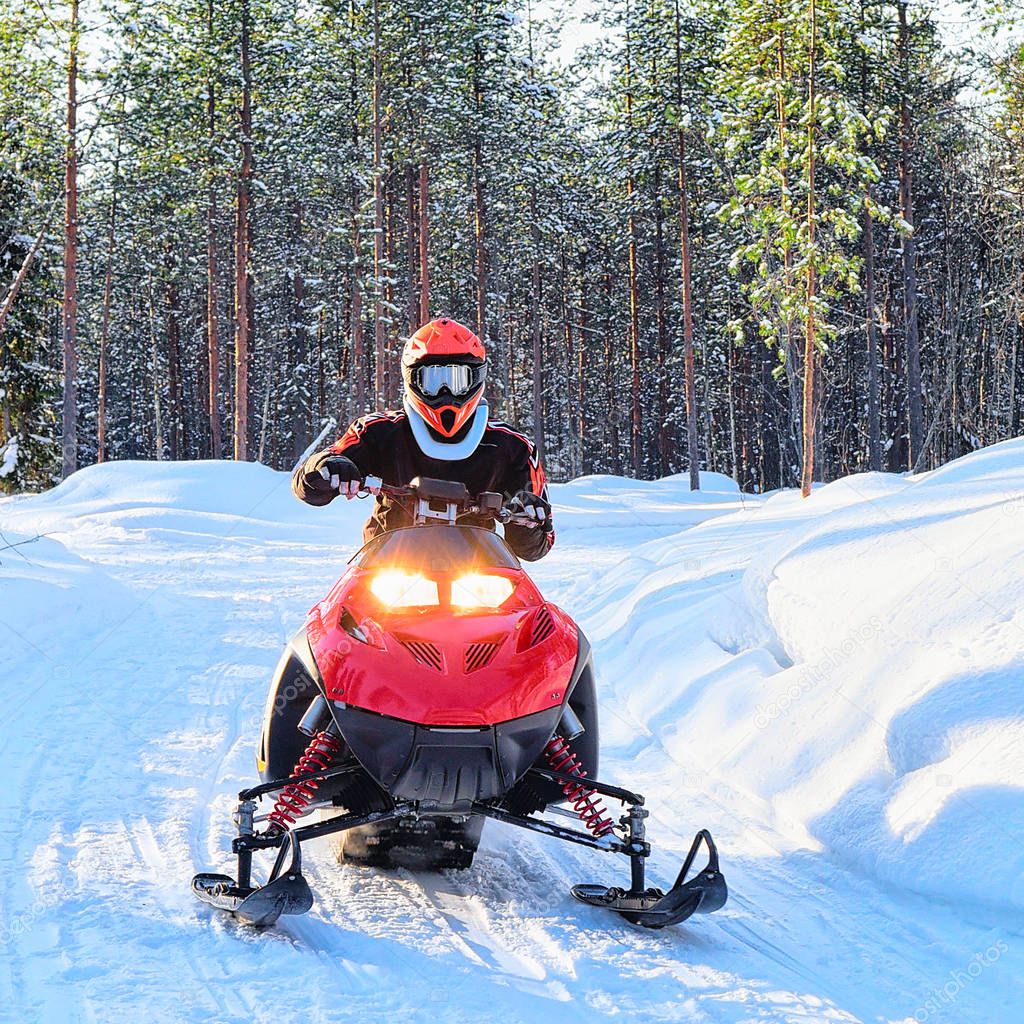 Woman riding red snowmobile on frozen lake at winter Rovaniemi