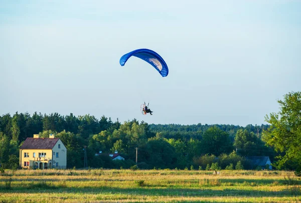 Paraglider lentää laskuvarjolla maaseudulla Puolassa — kuvapankkivalokuva