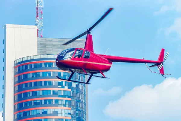 Şehir merkezindeki modern gökdelen yukarıda uçan kırmızı helikopter — Stok fotoğraf