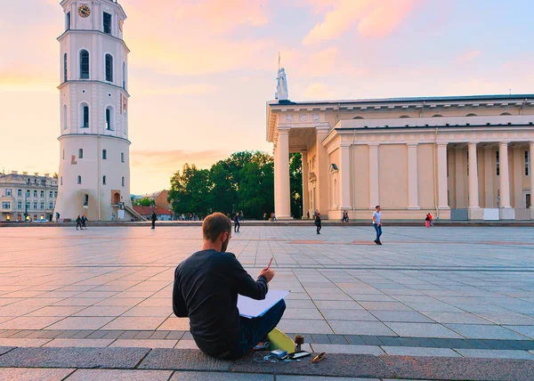 Man painting Cathedral Square and Bell tower Vilnius at sunset