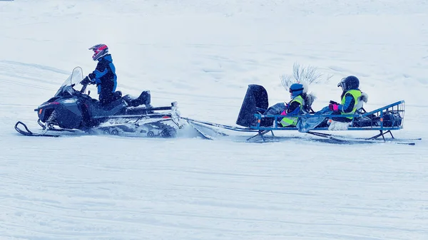Hombre montando motos de nieve y niños en carruaje invierno Rovaniemi — Foto de Stock