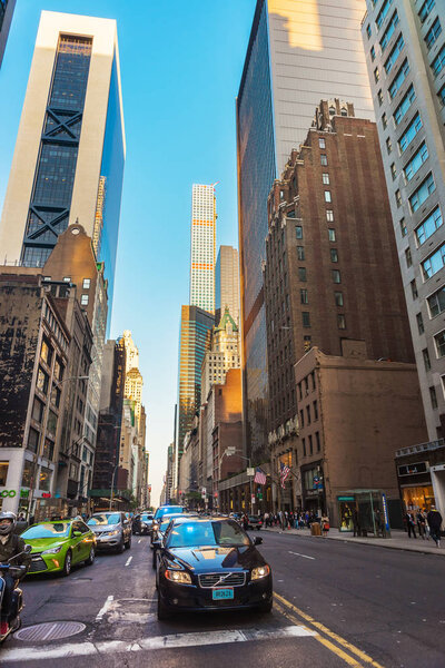 New York, USA - May 6, 2015: Intersection of Avenue of the Americas, or Sixth Avenue, and West 57th Street in Midtown Manhattan, NYC. 432 Park Avenue Building on the background. Tourists in the street