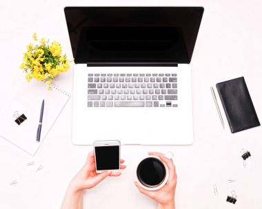 Telefon ve kahve dizüstü çiçek tutan kadın el ile çalışma alanı