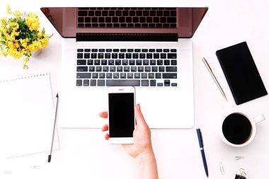 Telefon laptop klavye sarı çiçek tutan el ile çalışma alanı