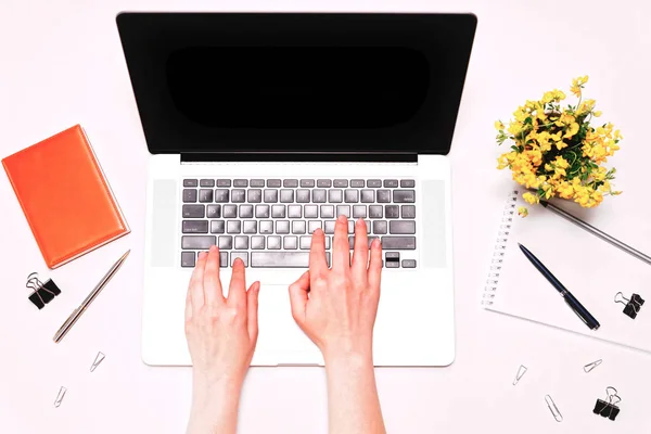 Espacio de trabajo con las manos femeninas trabajando en el teclado portátil flores amarillas — Foto de Stock