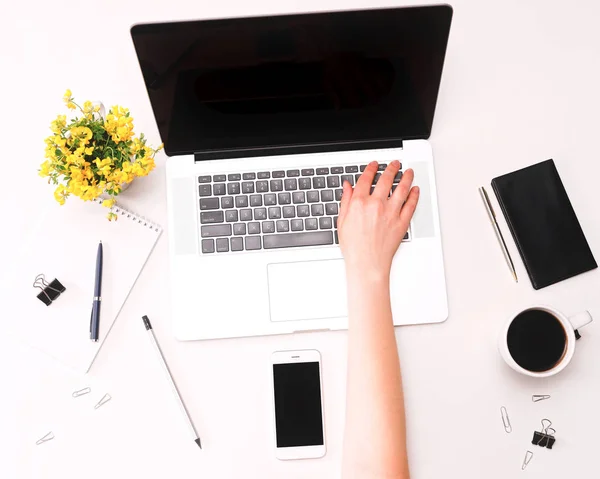 Espacio de trabajo con la mano de mujer en el teclado portátil flores de café móviles — Foto de Stock