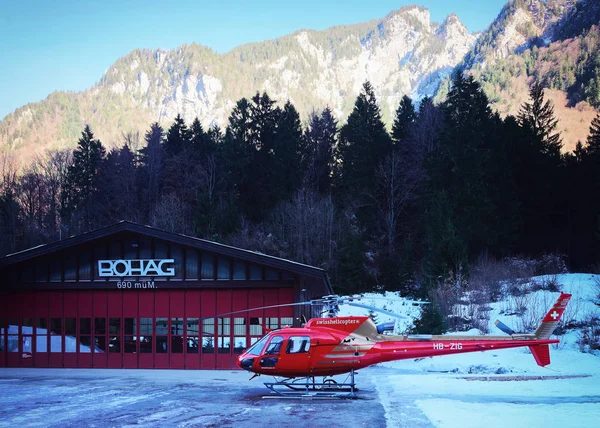 Helicóptero rojo en helipuerto alpino suizo en invierno Gsteigwiler —  Fotos de Stock