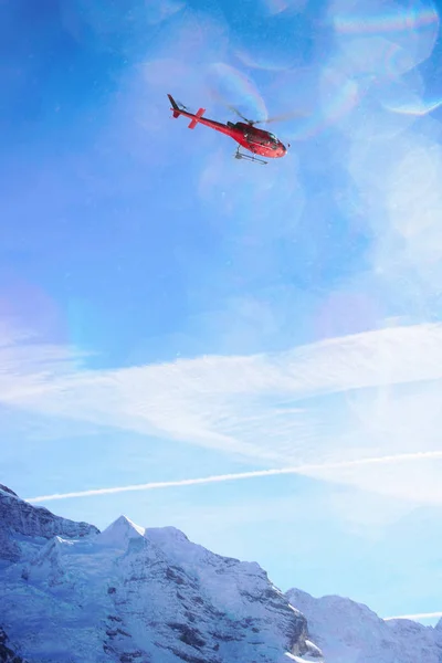 Красный вертолет пролетел над швейцарской альпийской горой Mannlichen в — стоковое фото