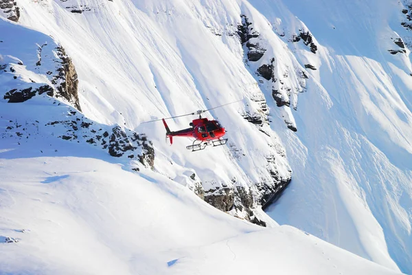 Röd helikopter flyger nära Swiss Alpine mountain Mannlichen i w — Stockfoto