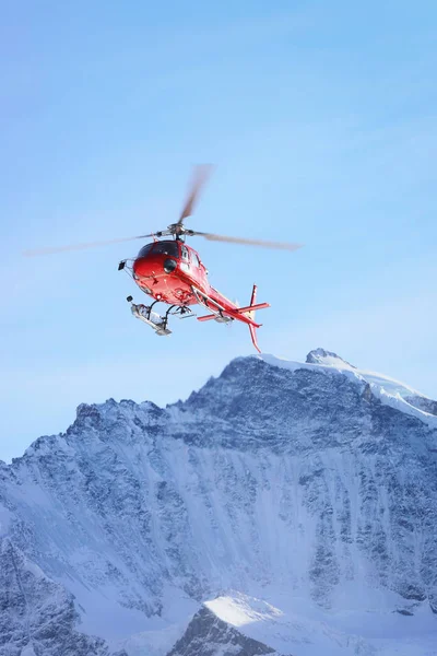 Helicóptero rojo en las montañas alpinas suizas en invierno Gsteigwiler — Foto de Stock