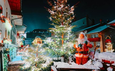 Santa Claus and Christmas tree in Gruyeres winter night new clipart
