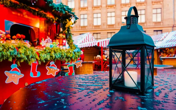 Фонарь с горящей свечой на столе на рождественской ярмарке рефлексов — стоковое фото