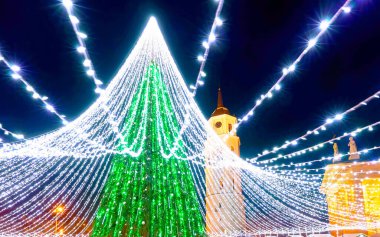 Vilnius Noel pazarındaki insanlar ve çelenk refleksiyle Noel ağacı