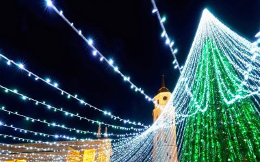 Vilnius Noel pazarındaki insanlar ve çelenk refleksiyle Noel ağacı