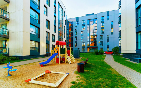 Modern residential apartment flat house building and children playground reflex
