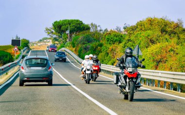 Costa Smeralda refleksinde motosikletler ve arabalar yolda.