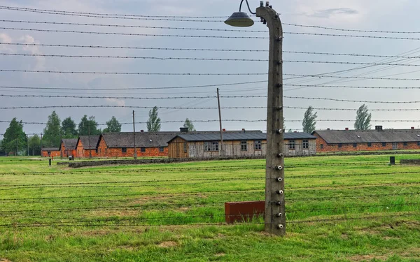 Budynki baraku i drut kolczasty w obozie koncentracyjnym Auschwitz Birkenau — Zdjęcie stockowe