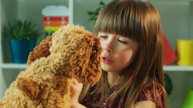 Sevimli küçük kız onun oyuncak oyuncak ayı sevgi dolu. Sarılma, oyuncak ayı öpüşme küçük kız. Yakın çekim. Çocuk odası