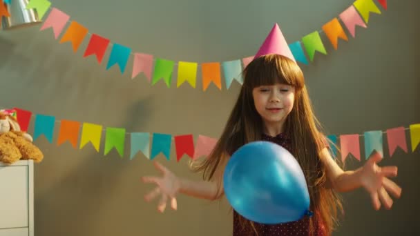 Lustiges kleines Mädchen tanzt und springt mit blauem Luftballon auf Geburtstagsparty — Stockvideo