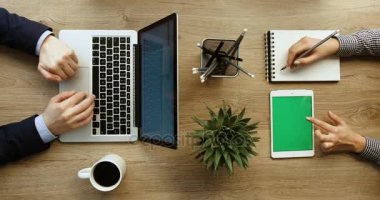 Üstten Görünüm adam el laptop ve kadın elle tablet ile Ofis Masası üzerinde çalışma çalışma. İş. Ağır çekim. Yeşil ekran