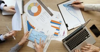 Üstten Görünüm eller. Finansal Tablolar ve grafikler, işaret ve tablet ve laptop, defter, ofis ahşap büro yazma çalışma kontrol iş takım. Hızlı hareket. Zaman atlamalı