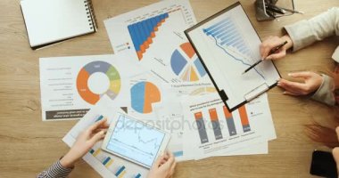 Üstten Görünüm eller. İş erkek ve kadın mali tablolar ve grafikler, işaret ve çalışma tablet ve laptop, hızlı hareket ile kontrol ediyor. Zaman atlamalı. Takım çalışması