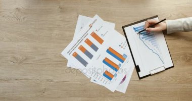 Üstten Görünüm eller. İş takım mali tablolar ve grafikler, işaret ve tablet, not defterinde office ahşap masanın üstüne yazma çalışma ile çalışma. Hızlı hareket. Zaman atlamalı