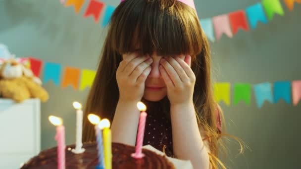 Chica bonita pidiendo un deseo y soplando velas en el pastel de cumpleaños. Fiesta de cumpleaños. De cerca. Interior, fondo gris — Vídeos de Stock