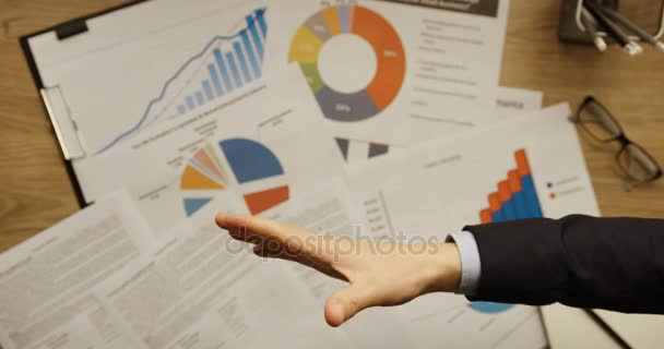 Top view of business man shaking hands with another business man at office desk with financial charts background. Hands top view. Slow motion. Handshake — Stock Video