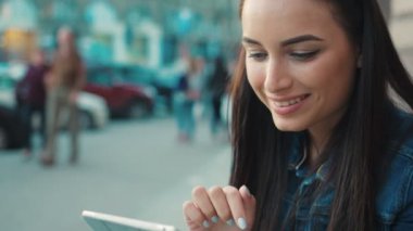 Sokakta merdivenlerde otururken tablet aygıtı kullanan güzel gülümseyen kadın. Okuma, dokunmatik ekran dokunarak, tarassut video kadın. Yakın çekim